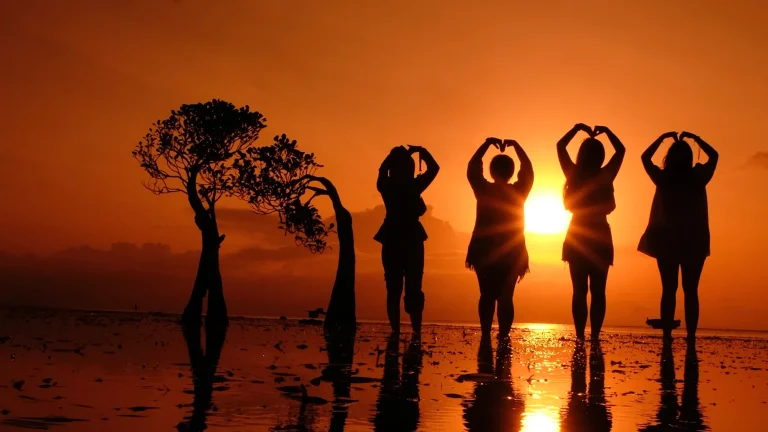 Travellers making heart shapes at sunset on Walakiri Beach, East Sumba