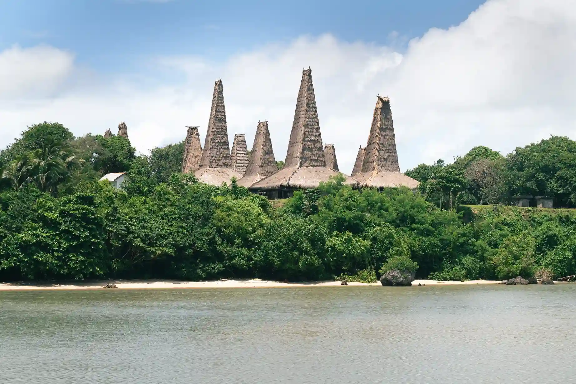 Tall thatched roofs of Ratenggaro village above the lagoon, West Sumba